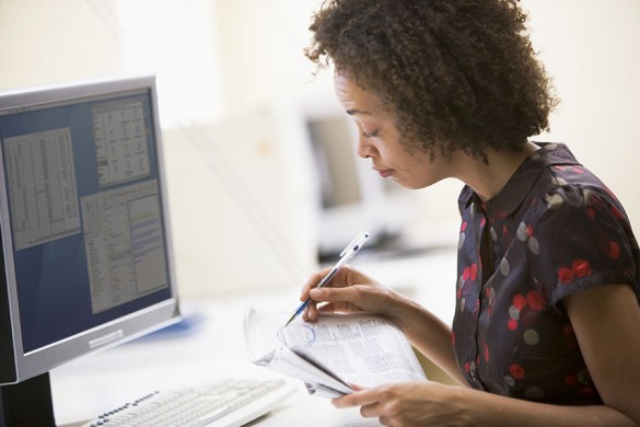 Woman in computer room circling items in newspaper